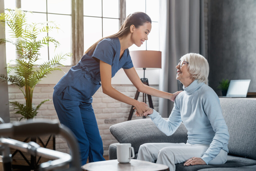 Nurse assisting an older woman at home, symbolizing compassionate palliative care and support for patients living with serious illness. PQLC is working to expand palliative care access.