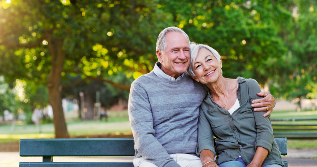 Older couple sitting together on a park bench, reflecting improved quality of life and emotional well-being through access to palliative care.
